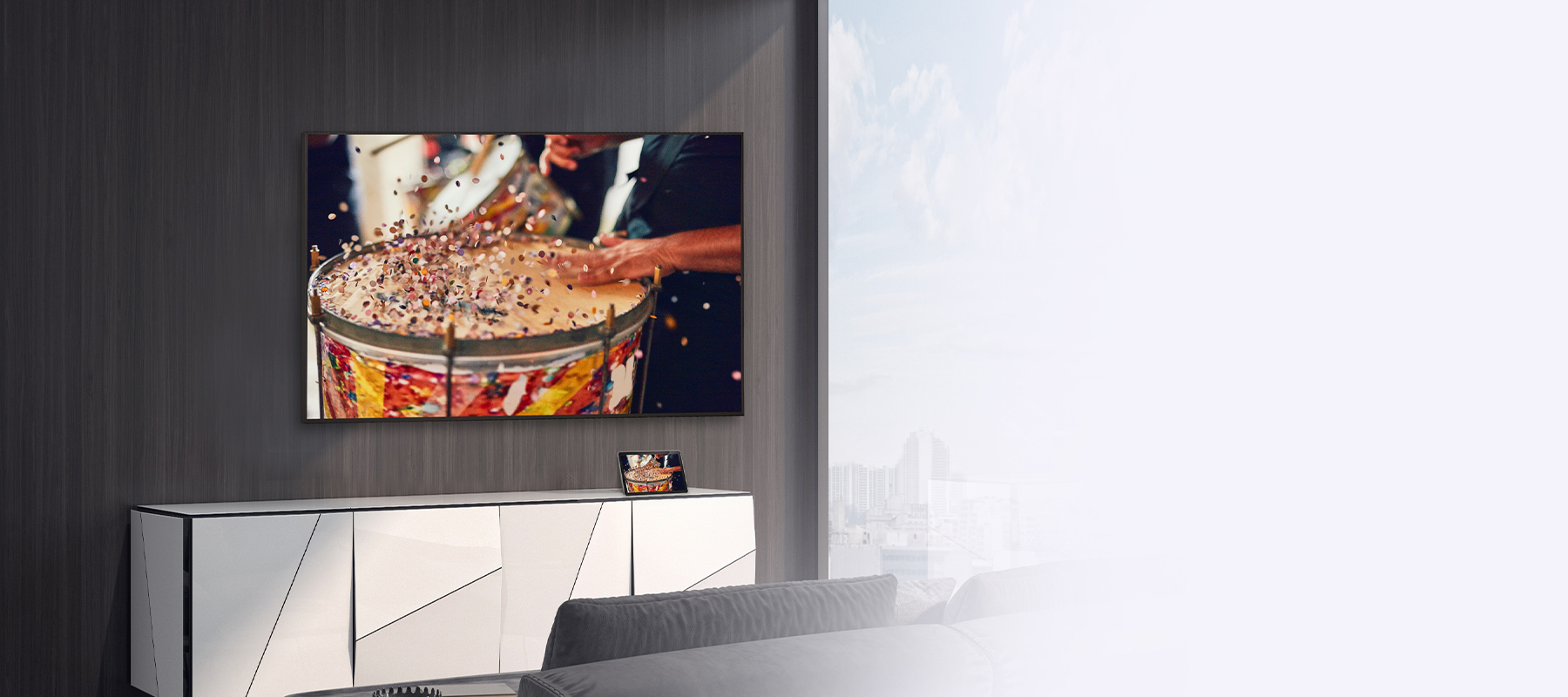 In the room, a wall-mounted TV is set up, with a tablet placed on the shelf. The tablet’s content is mirrored and displayed on the TV.